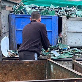 Worker sorting electronic waste and recycled materials in industrial bins